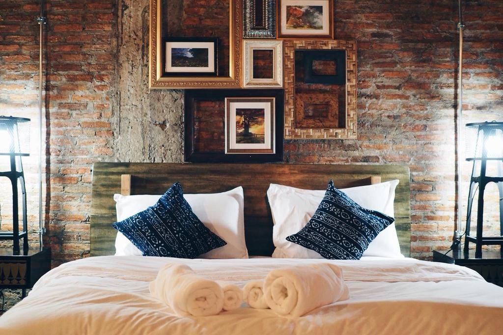 King bed against brick wall with framed pictures